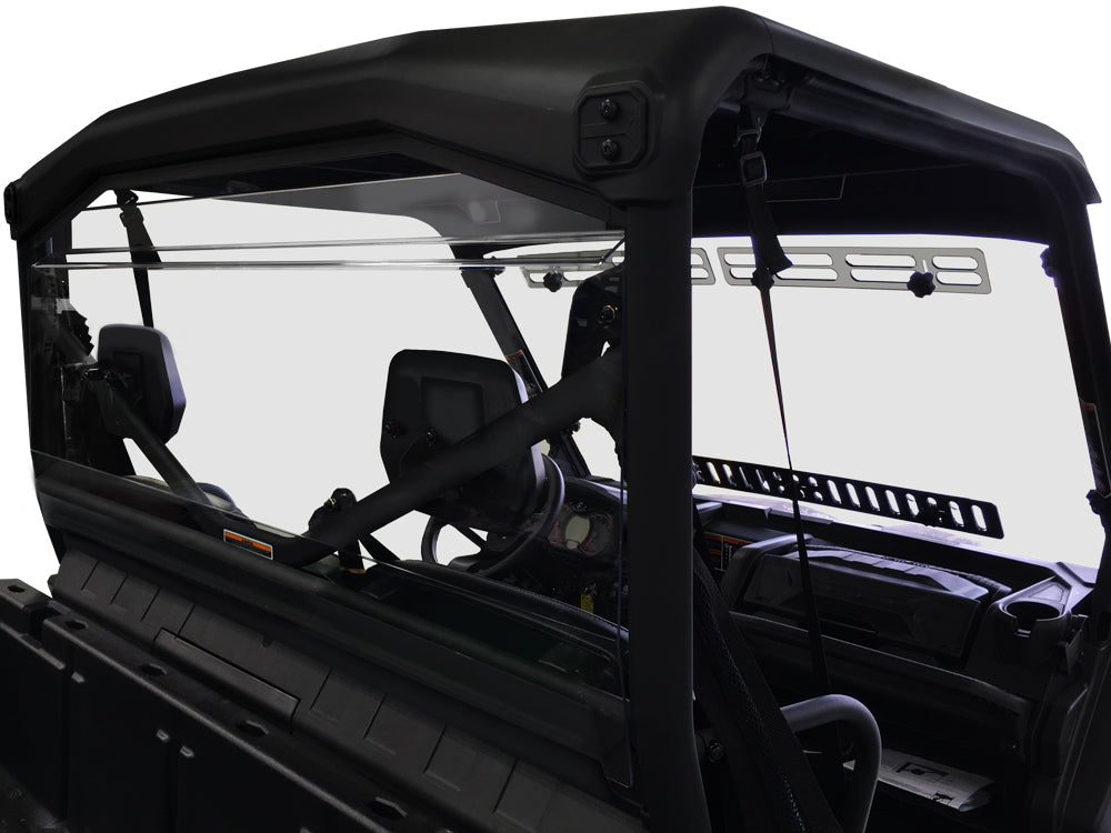 Close-up of the Can Am Defender Rear Windshield 2016+ installed on a black off-road utility vehicle interior, highlighting the steering wheel, dashboard, rearview mirror, and clear rear windshield against a white background.