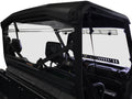 Close-up of the Can Am Defender Rear Windshield 2016+ installed on a black off-road utility vehicle interior, highlighting the steering wheel, dashboard, rearview mirror, and clear rear windshield against a white background.