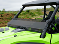 A Honda Talon 2019+ with a tinted half windshield is parked on dirt, featuring a black roof and visible seat and roll cage. The green off-road vehicle is set against grassy hills under a cloudy sky, shown from the front and side.