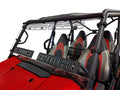 A close-up of a Kawasaki Teryx-4 featuring four bucket seats with black, gray, and red upholstery. It has a hard-coated, scratch-resistant full windshield with multi-vents and metal brackets. Shown on a white background.