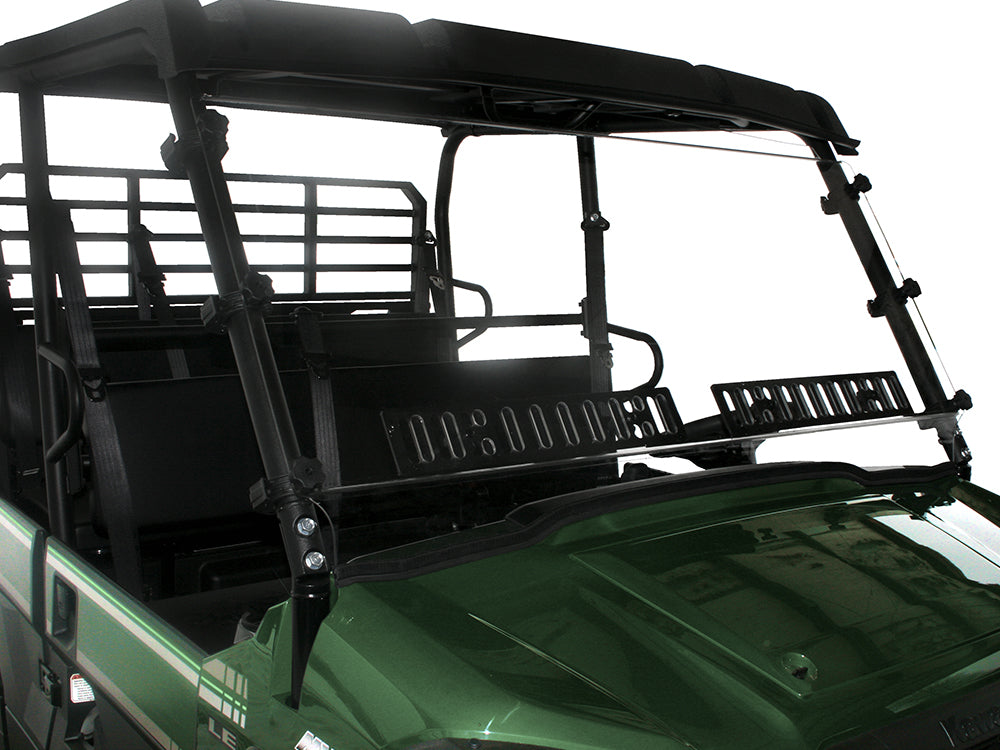 A close-up of a Kawasaki Mule Pro-Fxt with a hard-coated, scratch-resistant windshield featuring dual vents, black mounting brackets, protective roof, metal backrest guard, and visible hood and seating area against a plain white background.