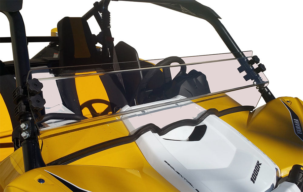 A close-up of a yellow and white off-road vehicle shows a Yamaha Yxz Hard Coated Scratch Resistant Half Shield (2016-2018) mounted on the front with black brackets. The vehicle features a black roll cage, seats, and visible steering wheel.