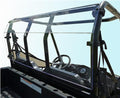 A Polaris Ranger Mid-Size (Round Tubing) Rear Window 2011-2014 With Round Tubing is installed on a black UTV, separating the cab with visible steering wheel and dashboard from the cargo bed, and is framed by metal bars and bolts.