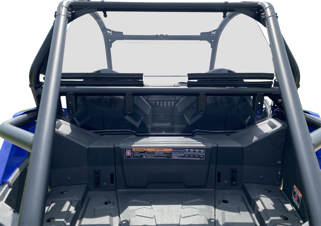 Close-up view of the rear cargo area of a blue off-road utility vehicle, showing the roll cage, black storage compartment, safety labels, and angular plastic panels. The background is plain white, highlighting the vehicle’s rugged design.