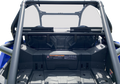 Close-up view of the rear cargo area of a blue off-road utility vehicle, showing the roll cage, black storage compartment, safety labels, and angular plastic panels. The background is plain white, highlighting the vehicle’s rugged design.