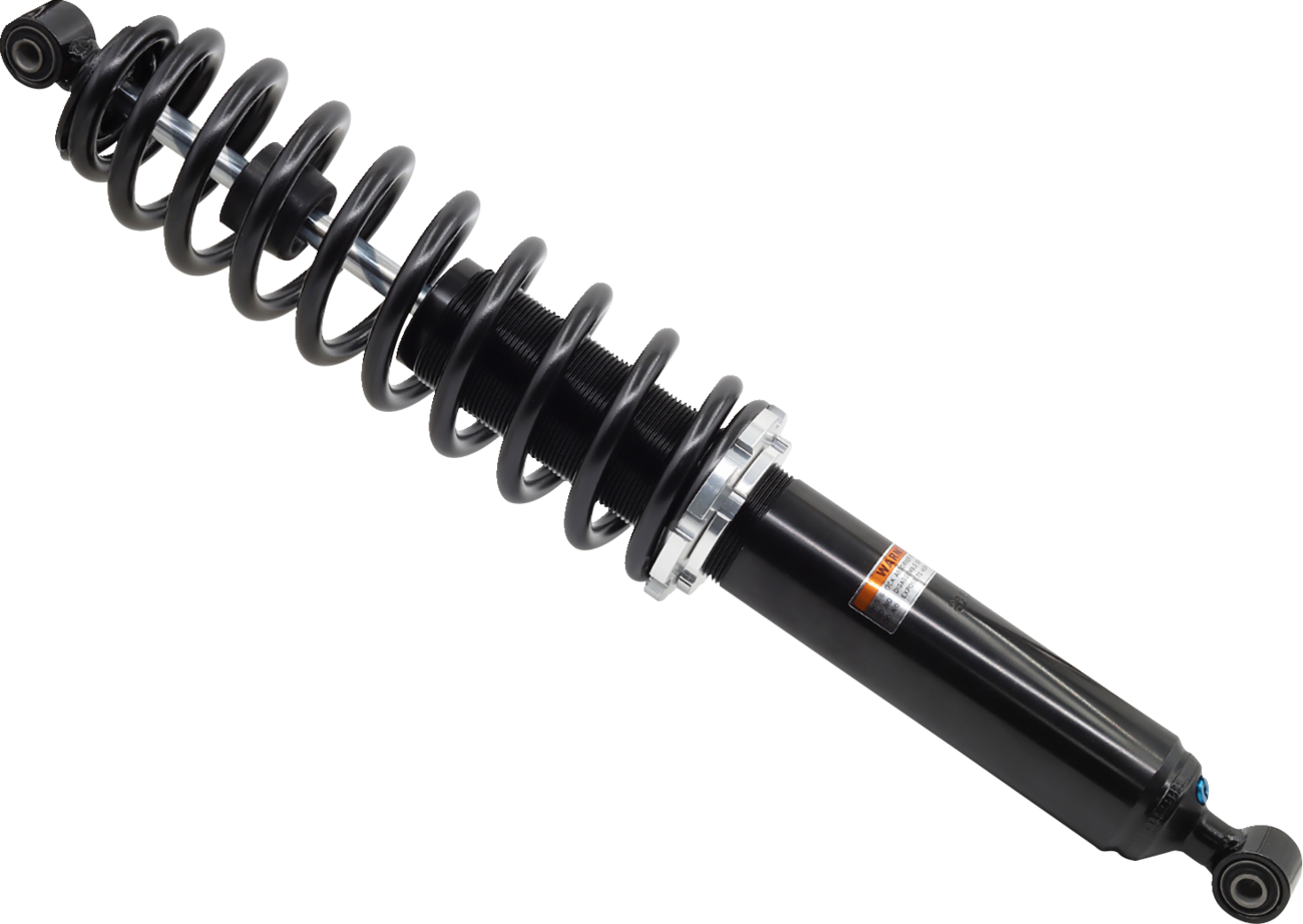 A black automotive shock absorber with a tightly coiled spring wrapped around its body is shown against a white background. The metal spring surrounds the cylindrical shock, which has a mounting eyelet at one end and a label with text on its side.