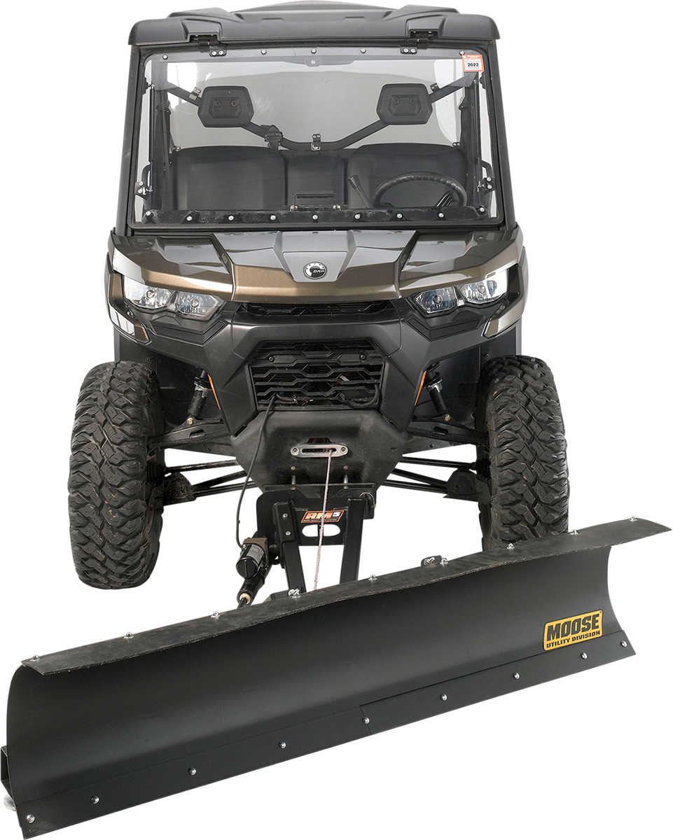 A black utility vehicle with large off-road tires is viewed from the front. It is equipped with a wide, attached snow plow blade labeled Moose Utility Division at the bottom. The plow is mounted and ready for clearing snow or debris.