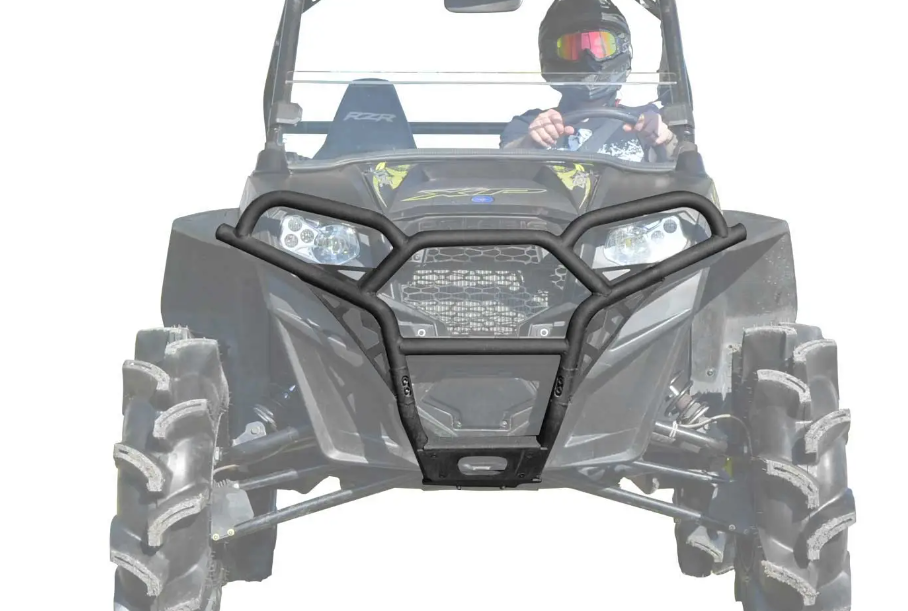 A helmeted driver in goggles operates a black off-road vehicle equipped with a Polaris RZR 800 Front Bumper and large, deep-tread tires, photographed head-on against a white background.