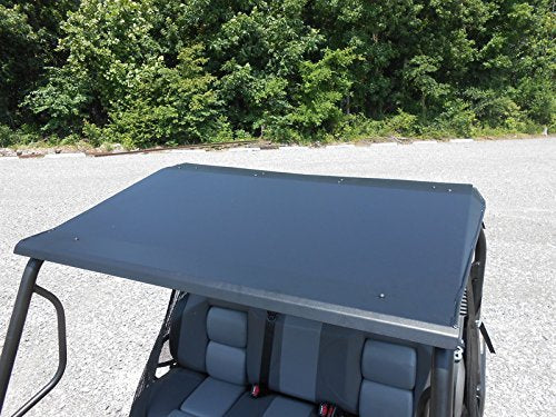 The Intimidator Single Cab Aluminum Top, in black, is installed over a four-seat utility vehicle with two-tone gray and black seats, shown parked on gravel against dense green trees and bushes.