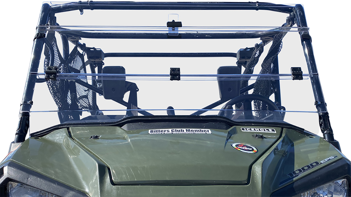 Front view of a green off-road vehicle with a transparent plastic windshield, two visible seats with mesh side panels, and several stickers on the hood, including ones reading Bitters Club Member and 1000cc. The background is plain white.