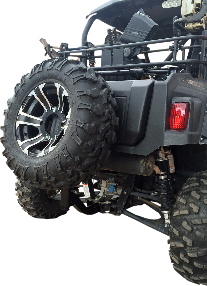 Close-up view of the rear side of an off-road vehicle, showing a mounted spare tire with a rugged tread, a red tail light, suspension coils, and parts of the undercarriage, all against a white background.