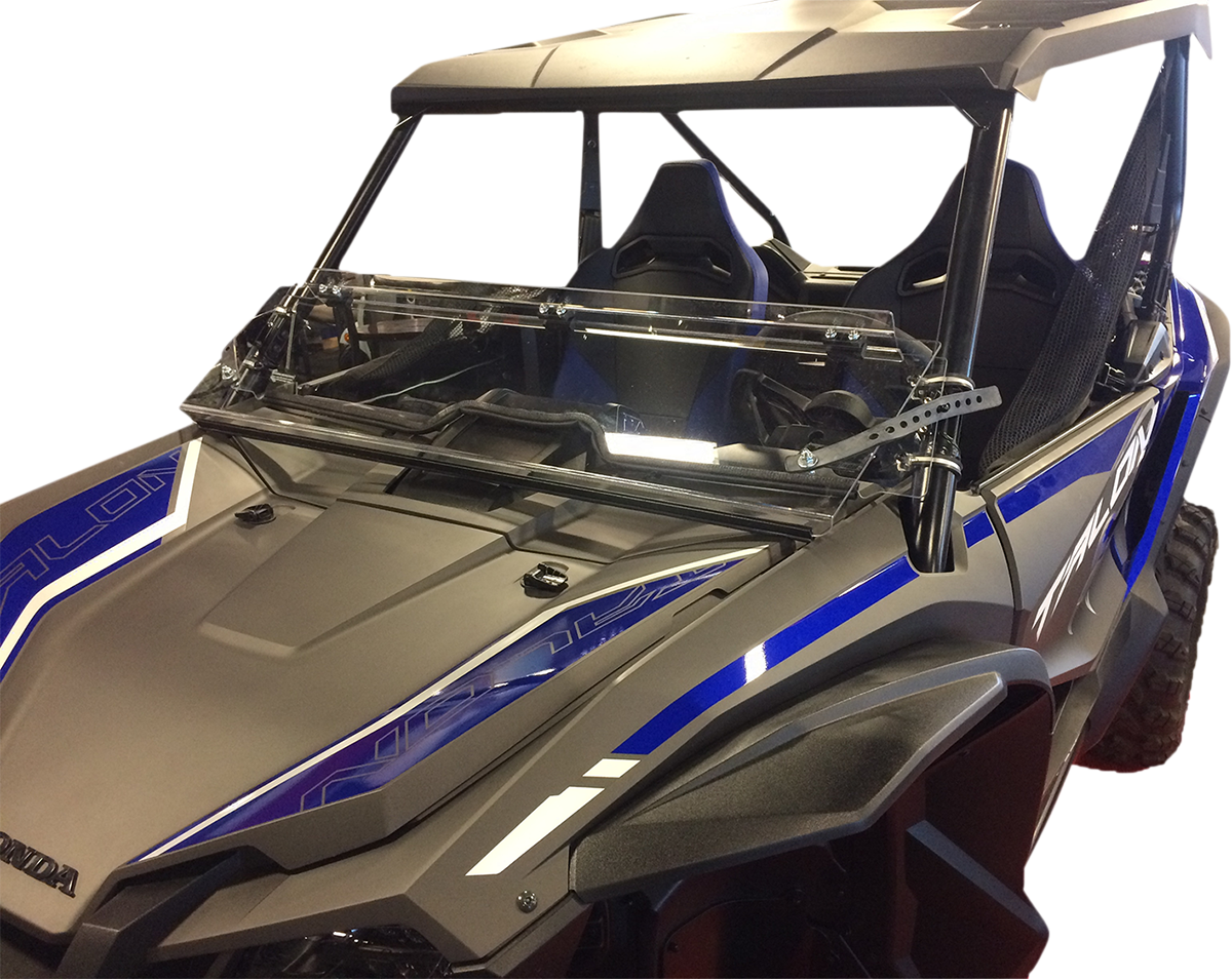 A black and blue off-road side-by-side vehicle with a transparent folding windshield and two bucket seats. The vehicle has angular, rugged features, a roof, and is photographed from the front left side against a white background.