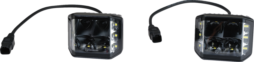 Two black square LED pod lights with clear lenses and attached black power cables, each ending in a rectangular connector. The lights feature multiple LED bulbs inside and vertical rows of smaller LEDs on both sides. The background is plain white.