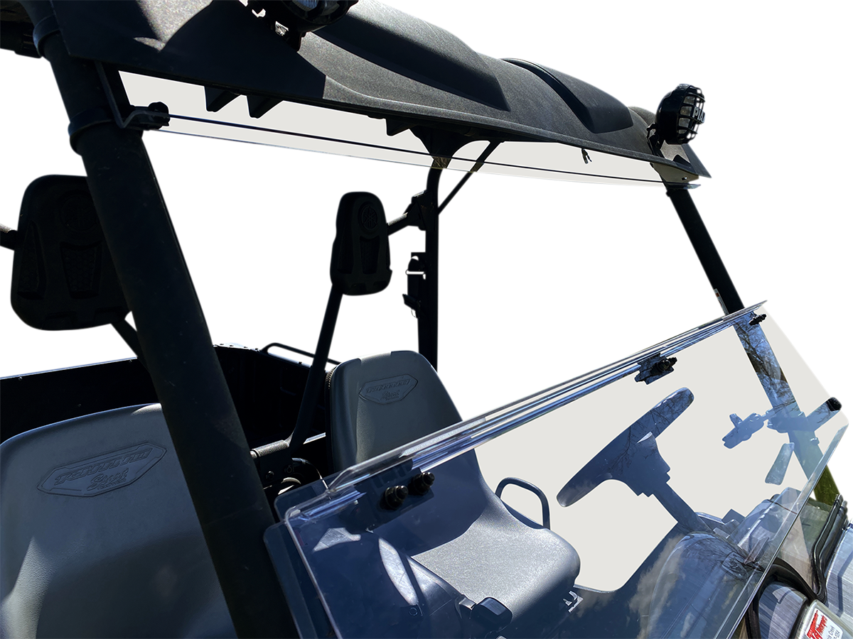 A close-up of a utility vehicle’s front interior shows two gray seats, a steering wheel, and a clear windshield with clamps. The vehicle has a black roof, overhead bars, and exterior lights mounted on top. The background is plain white.