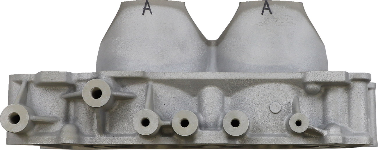 A close-up view of a metallic engine cylinder head, shown from the side. The surface has multiple round openings and protrusions, with two large domed sections marked with the letter A on top. The metal is unfinished, giving it a rough texture.