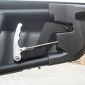A close-up of the Can Am Maverick X3 HMF Easy-Grip Aluminum Door Handle (2017+) and rod mechanism installed inside a black vehicle tailgate, highlighting the handle, rod, and mounting hardware against the plastic inner panel.