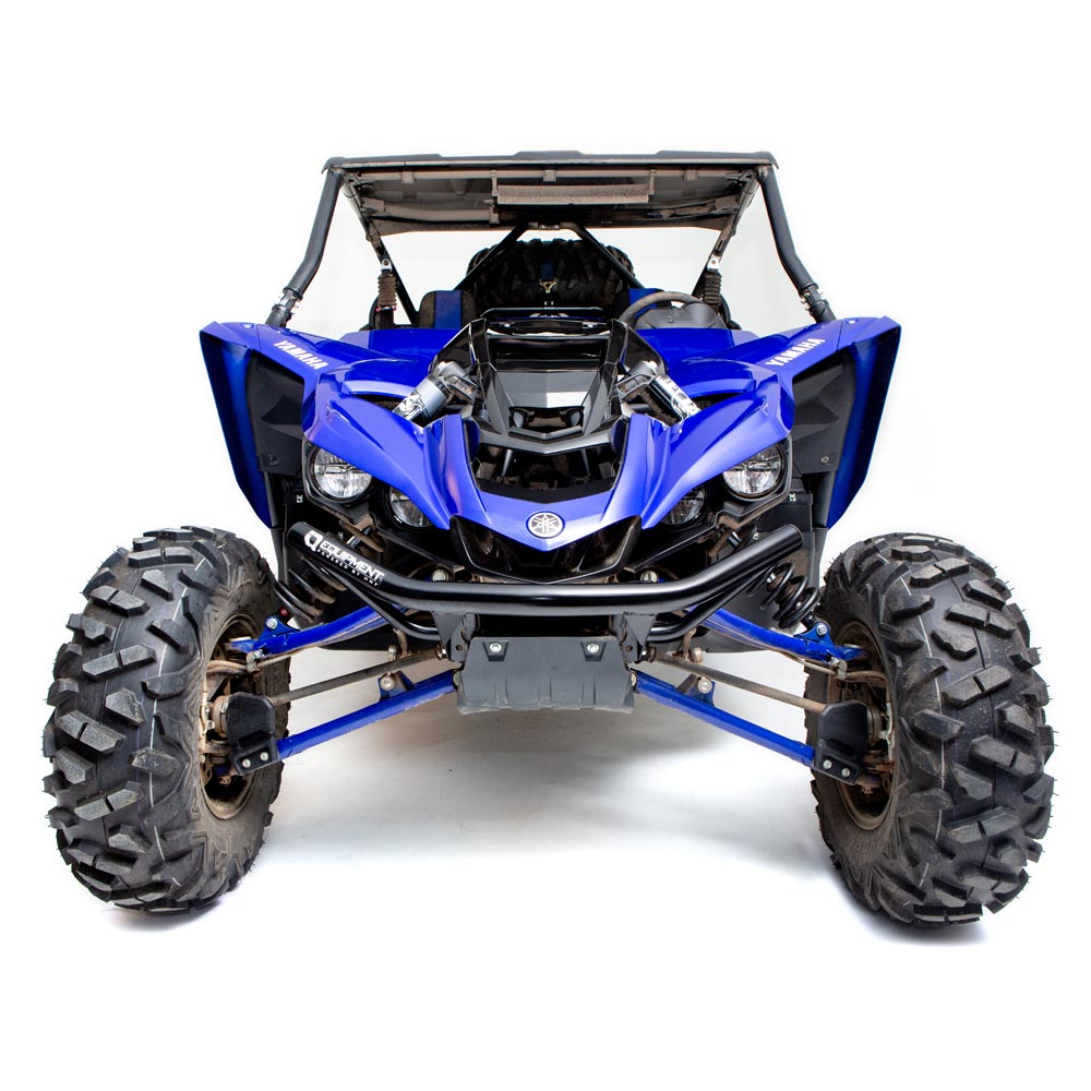 A front view of a Yamaha YXZ 1000R (2016+) featuring the HMF Defender heavy duty black front bumper, with rugged tires, exposed suspension, protective roof, sporty angular design, headlights, visible engine parts, and Yamaha logo on the nose.