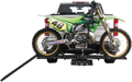A green and yellow motocross dirt bike with the number 48 is mounted on a black hitch rack attached to the rear of a white pickup truck. The bike is secured, and a ramp extends from the rack to the ground for loading and unloading.