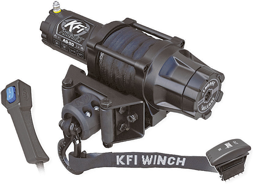 A black 5000 Assault Series Winch with wrapped cable, mounted bracket, and attached hook. At left is a handheld remote with blue buttons; at right are a “KFI WINCH” strap and a wired control switch.