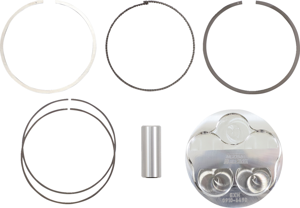 Five metallic piston rings of varying thickness and size are arranged in pairs in the top two rows, a cylindrical wrist pin is centered below them, and a reflective piston head with engraved markings is at the bottom right against a white background.