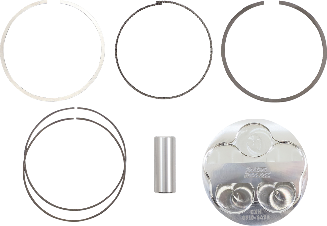 Five metallic piston rings of varying thickness and size are arranged in pairs in the top two rows, a cylindrical wrist pin is centered below them, and a reflective piston head with engraved markings is at the bottom right against a white background.
