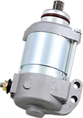 A shiny silver and gray automotive starter motor with a cylindrical body, mounting bracket, visible bolts, and electrical terminal. The metal surfaces are clean and reflective, showing industrial detailing and mechanical components. The starter is set aga