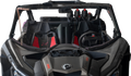 A front view of a rugged off-road vehicle with two black and red bucket seats, a steering wheel on the right, and three helmets secured behind the seats; the windshield and vehicle interior appear dusty.