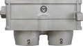 Close-up of a metallic industrial part with a light gray finish. The part has two cylindrical outlets at the bottom, each marked with the letter B. A round logo with a stylized M is centered on the raised section above the outlets.