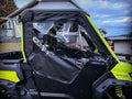 A Can-Am Defender with yellow and black accents is parked outside a house, equipped with Can-Am Defender Framed Upper Soft Doors for OEM Lower Half Doors featuring clear plastic windows and black trim. Cloudy skies are in the background.