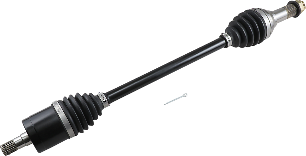 A black automotive drive shaft with metal ends and rubber CV joint boots is shown diagonally on a light background. A small metal pin lies nearby for scale. The shaft is clean and appears new, with visible grooves and mechanical details.
