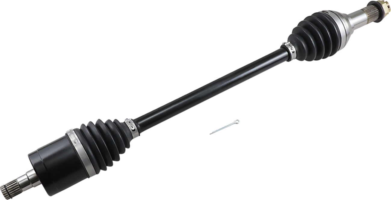 A black automotive drive shaft with metal ends and rubber CV joint boots is shown diagonally on a light background. A small metal pin lies nearby for scale. The shaft is clean and appears new, with visible grooves and mechanical details.