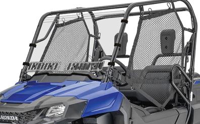 A close-up of a Honda Pioneer 700 Full Windshield w/Vent (Hard Coated Scratch Resistant, 2013+) shows the rugged blue off-road vehicle’s front with two black mesh side doors, angular lines, visible seats, roll cage, and durable windshield.
