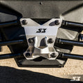 Close-up of the S3 Power Sports 2017+ Can-Am Maverick X3 HD Pull Plate, a silver metal bracket with the S3 logo and star, secured by six black bolts to a black frame—part of an off-road vehicle’s suspension system on concrete.