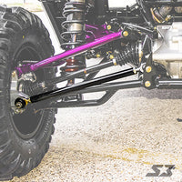 Close-up of S3 Power Sports 2013+ Can-Am Maverick X Ds Radius Rods’ front suspension, showcasing purple and black control arms, coilover shock, and a large rugged tire on the left, highlighting the rods’ connection to the chassis.