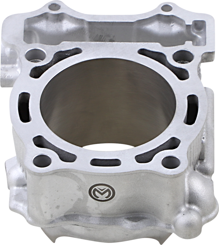 A close-up of a silver metal engine cylinder block with a large central bore, multiple bolt holes around the rim, and a small engraved logo on the lower front side. The block has a smooth machined surface and visible contours for mechanical fitting.
