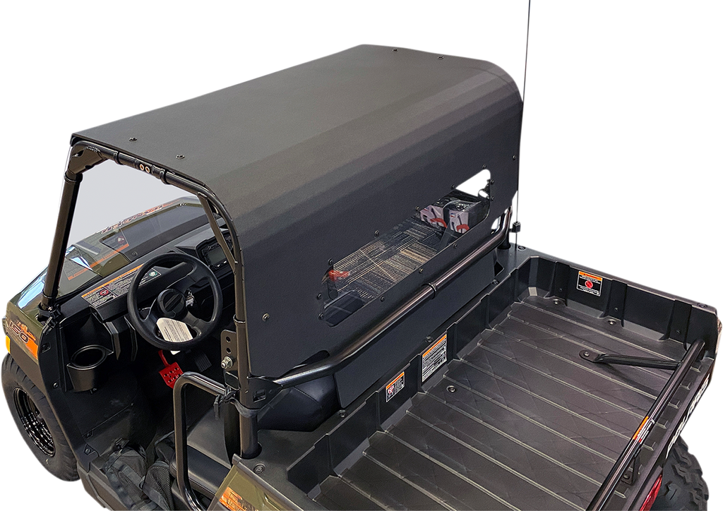 A black utility vehicle with a hard, matte-finish roof covers the cabin and extends over the cargo bed. The bed is empty and ribbed for grip. The cabin has a steering wheel and visible dashboard controls. The background is plain and light-colored.
