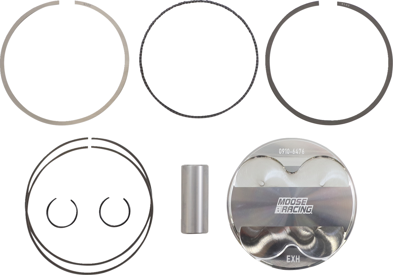 A motorcycle piston kit laid out on a white background includes a shiny piston engraved with “MOOSE RACING EXH,” a piston pin, two circlips, and two sets of piston rings, all arranged in an organized manner.