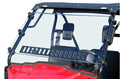 A close-up of the Honda Pioneer 500 Full Windshield W/Vent—Hard Coated Scratch Resistant (2015+) shows its clear, vented glass framed in black metal with clamps, atop a red hood and an interior featuring black seats with a central headrest.