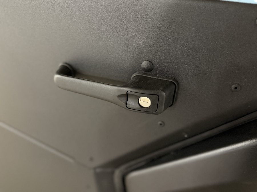 A close-up of the Can Am Defender Full Aluminum Door Kit (2 Door), showing a black manual window crank handle with a round metallic center and matte finish on the textured black aluminum door panel. Converts from full to half door.