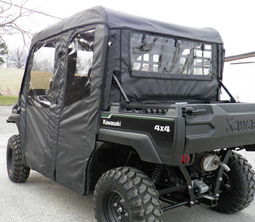 A black Kawasaki Mule Pro-FXT with off-road tires is parked on pavement, featuring an open cargo bed and fitted with a full cab enclosure for existing windshield, including clear plastic windows on the sides and back.