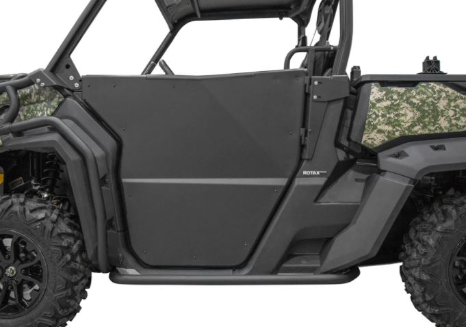 Side view of a Can Am Defender HD5/HD7/HD8/HD9/HD10 with Rival Powersports half doors, matte black step bar, camo rear panels, knobby tires, and open cab, emphasizing utility and durability for tough outdoor terrain.