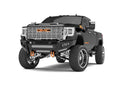 A lifted black GMC 2500 pickup with large chrome wheels and orange accents features a 2020+ Identity Front Bumper, shackles, double cube light pods, beauty ring, and hardware kit—perfect for rugged terrain and off-road style.