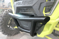 Close-up of a Short Front Bumper Kit for Polaris RZR XP1000 (2019-2021) in yellow, showing the sturdy black metal brush guard with welded joints, triangular support design, and part of the rugged tire and grille in the background.