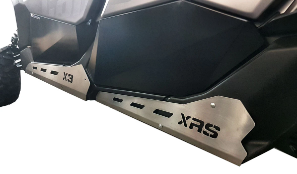 Close-up of black Can Am Maverick X3 Max 4 Seater with Rock Sliders Kit installed. The silver sliders have vent-like cutouts and bold X3 and XRS laser-cut text, indicating vehicle compatibility. White background.