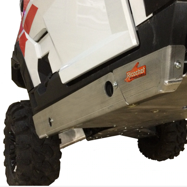 Close-up, low-angle shot of a white Polaris General XP 4 1000 (2020-2022) with red accents, showing a silver 2-Piece Aluminum Rock Slider Skid Plate installed for protection. A rugged black tire appears on the left.