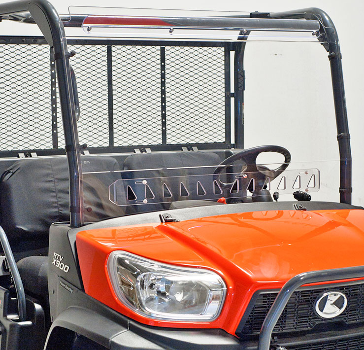 A bright orange RTV X900 features a Quantum Coated Vented Windshield, black grille, clear windshield, mesh rear panel, black bench seats, right-side steering wheel, headlights, and “RTV X900” model label on the side.