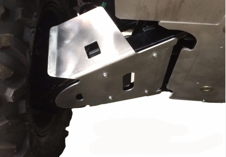 Close-up of 4-Piece A-ARM & CV Boot Guards for 2022-Current Honda Pioneer 1000, mounted under the vehicle near a rugged tire. Angular, bolt-secured guards with cutouts shield suspension and drivetrain components.