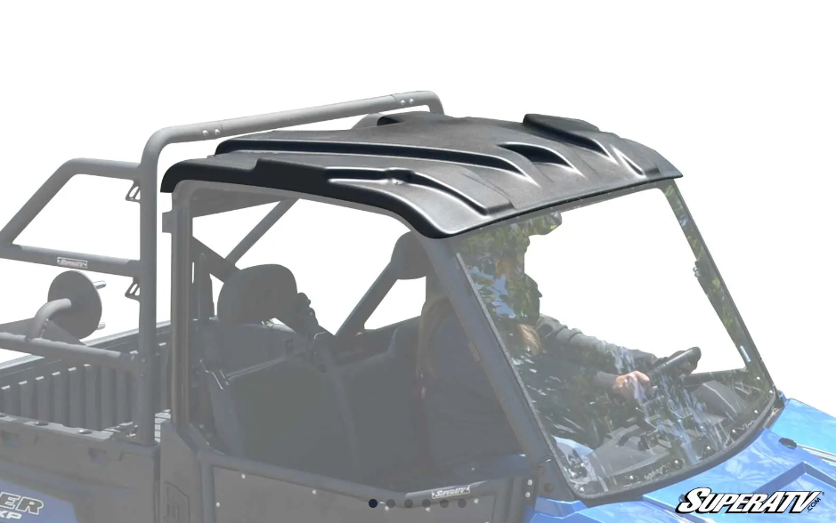 A person drives a blue off-road utility vehicle with a Polaris Ranger Fullsize Plastic Roof in black and a clear windshield. It has a protective roll cage, open cargo bed, and the SuperATV logo appears in the bottom right corner.