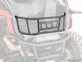 A SuperATV Honda Talon 1000 Bed Enclosure, made of black metal with horizontal and vertical bars and a central rectangular plate, is installed above the rear bumper of a Honda off-road vehicle. The background appears slightly faded.