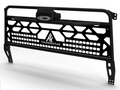 The 2016+ Can-Am Defender Winch Headache Rack (Black) features a rugged black metal design with geometric cutouts, angled side supports, a white THUMPER FAB logo at the center, and a top-mounted LED light bar for an industrial look.